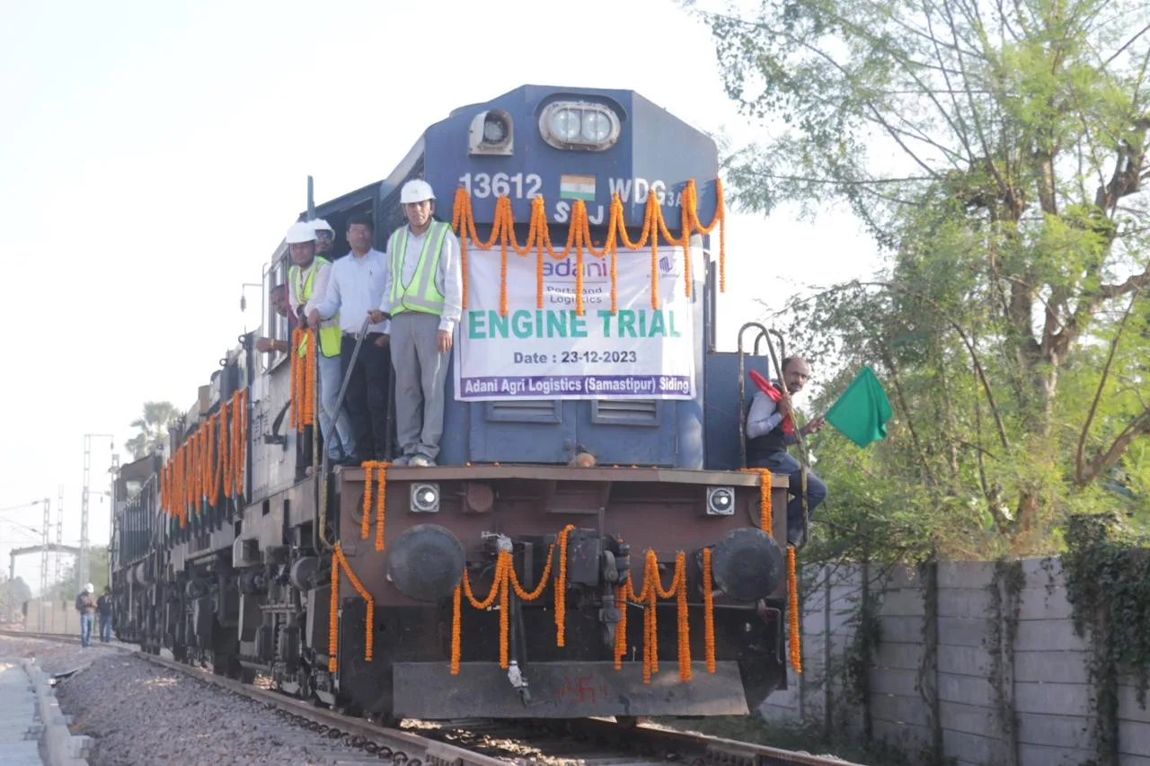 Decorated locomotive departing on its engine trial run with a flagman on the siding