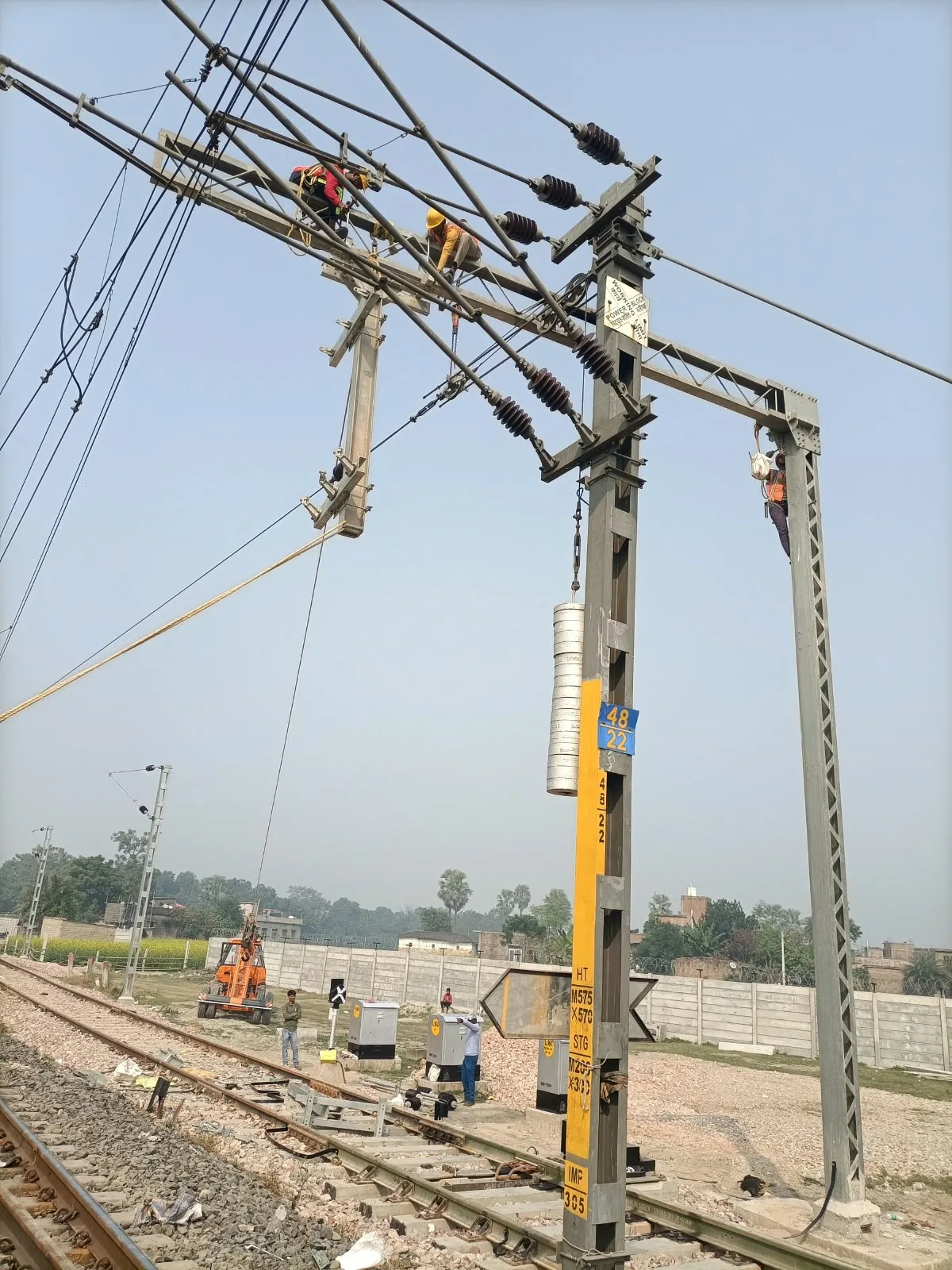 OHE mast erection alongside an active railway line